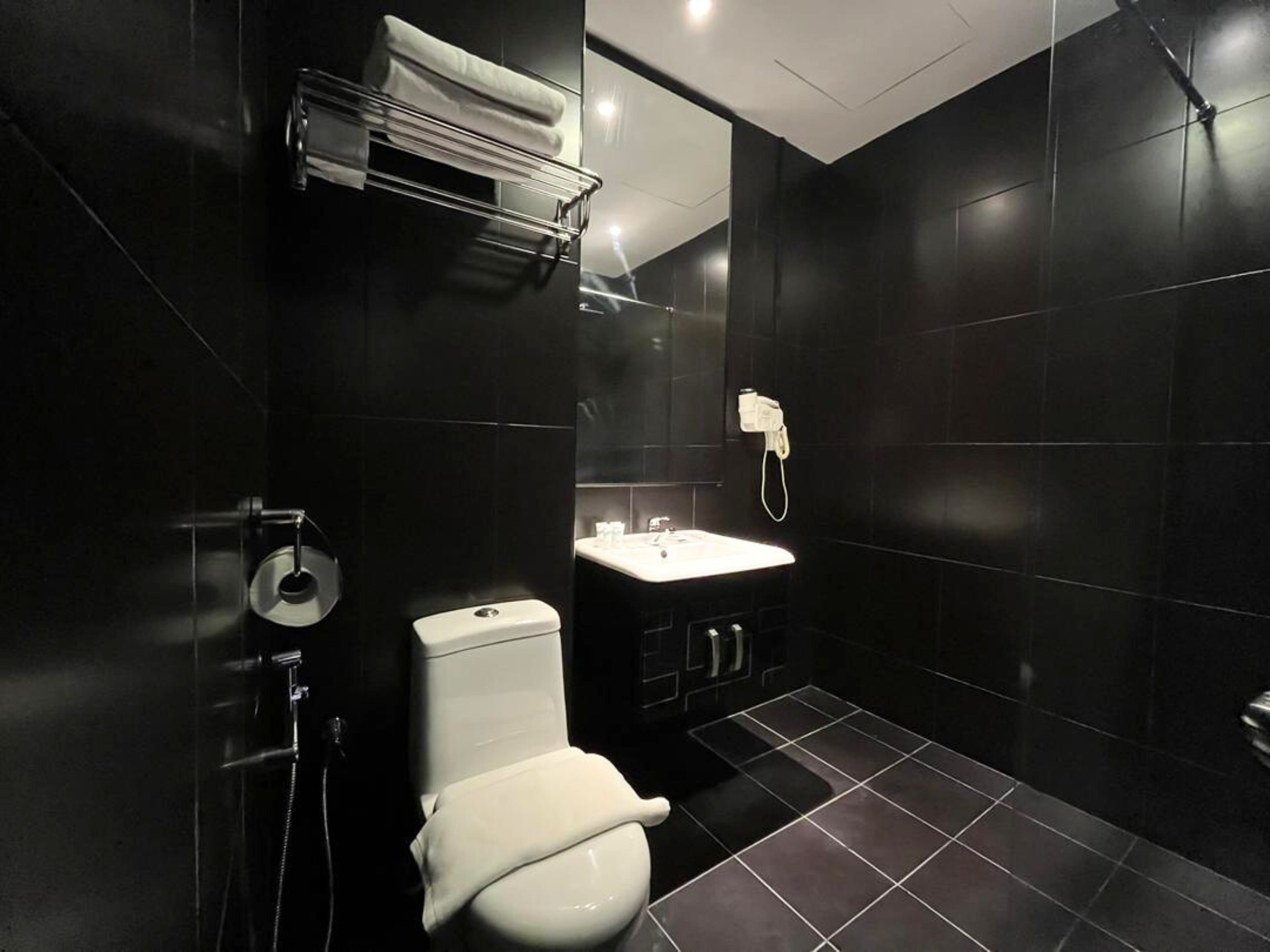 A modern bathroom with a toilet, sink, and towel rack.