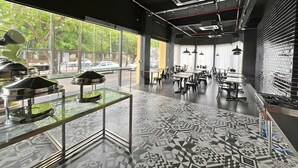 A modern restaurant interior with a patterned floor, glass display cases, and a view of the street outside. - The Estella Hotel Klang (Klang)