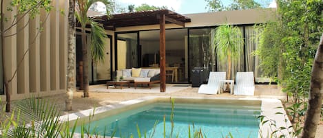 A pool with a pergola, a covered seating area, and a view of the house.