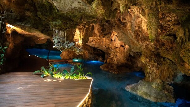 L’intérieur d’une grotte, avec une terrasse en bois et une petite piscine.