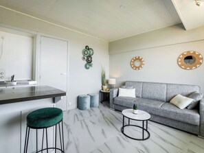 Un salon moderne avec un canapé gris, une table basse ronde et un tabouret vert.