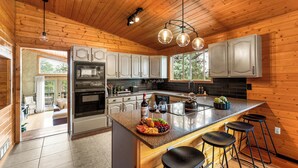 Una cocina moderna con paneles de madera, electrodomésticos de acero inoxidable y una isla central con taburetes.