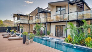 Une maison moderne dotée d’une piscine, d’un espace salon extérieur et d’un aménagement paysager luxuriant.