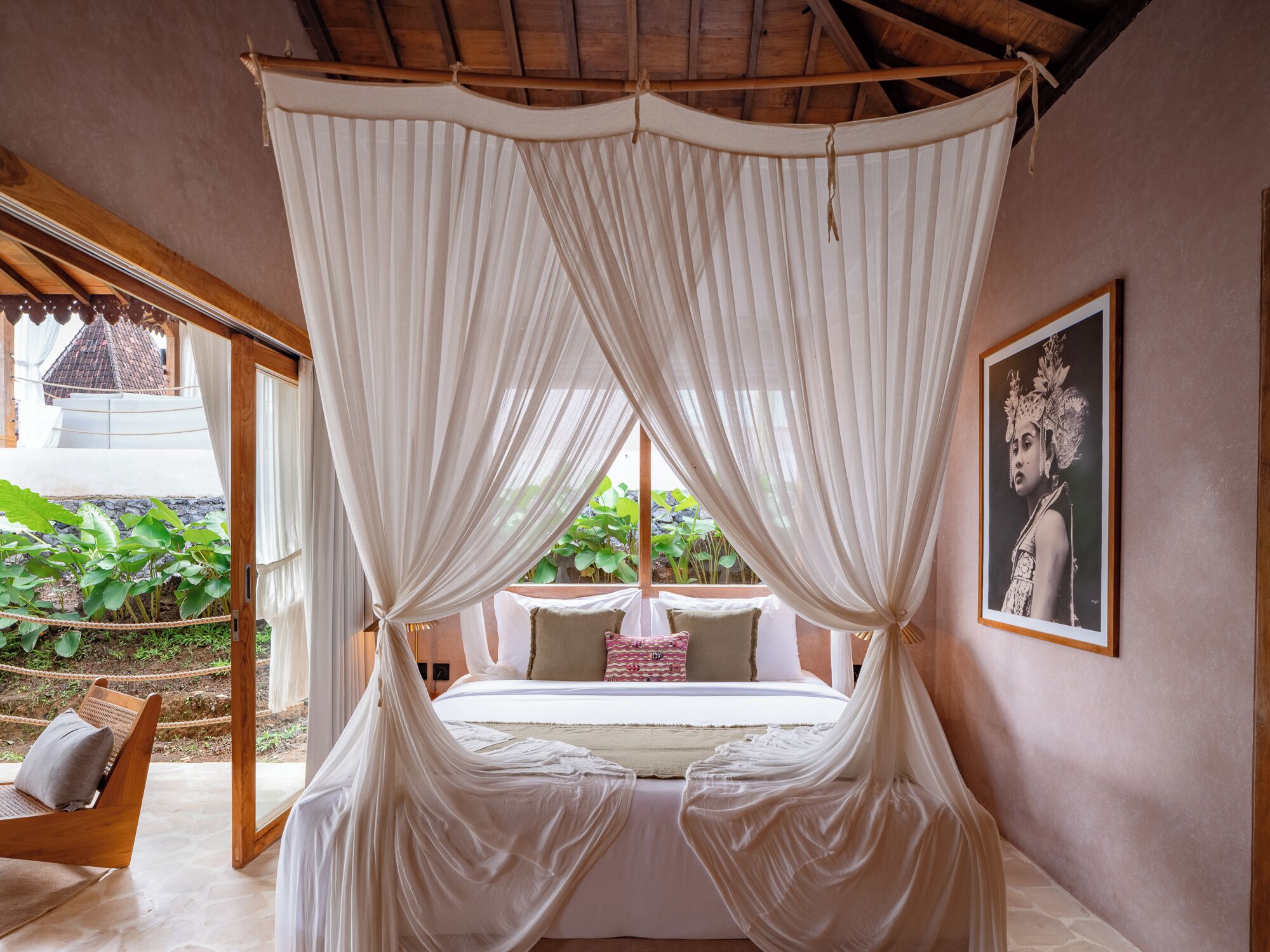 Un dormitorio con cama con dosel, vista a zonas verdes y un cuadro en la pared.