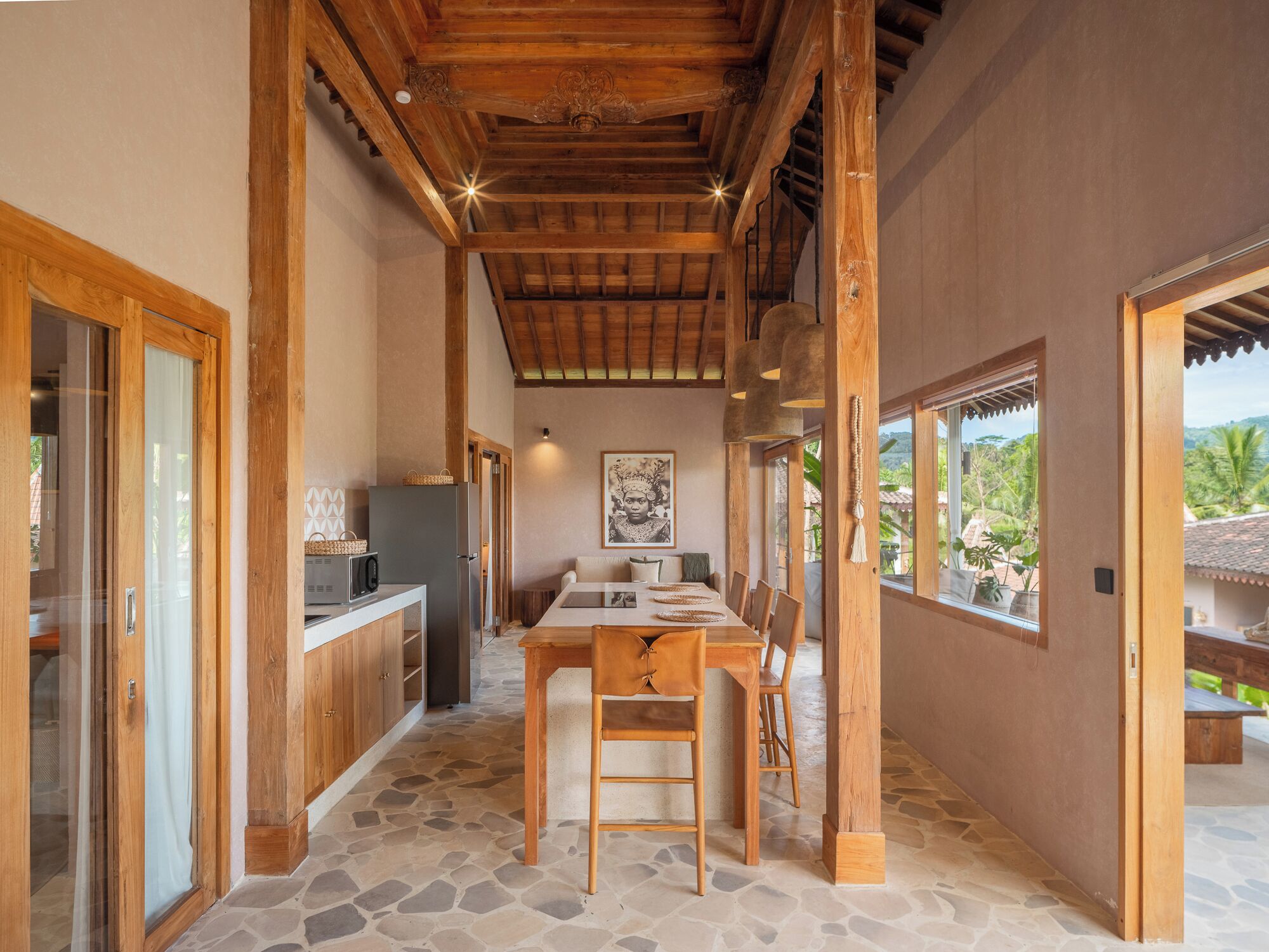 Una cocina con suelo de piedra, vigas de madera y una zona de comedor con mesa y sillas.