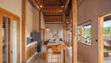 Una cocina con suelo de piedra, vigas de madera y una zona de comedor con mesa y sillas.