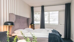 A hotel room with a bed, two bedside lamps, a window with curtains, and a view of the outside. - 4 Person Holiday Park Home in Give (Give)