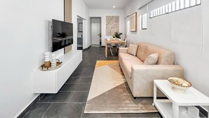 A modern living room with a sofa, a TV, and a dining area in the background. - Casa Canova | Duplex Full Home For 14PPL @San Juan (San Juan)