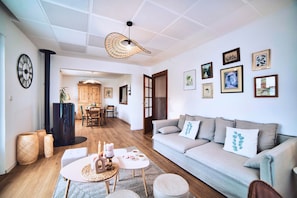 A modern living room with a sofa, a coffee table, and a dining area with chairs and a table.