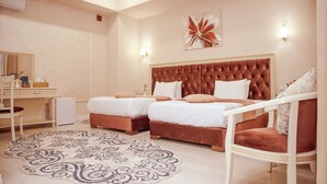 A hotel room with two beds, a desk, a chair, and a decorative rug. - al Madina Hotel Samarkand  (Samarkand)