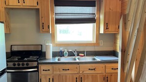 Una cocina con armarios de madera, una estufa, un fregadero y una ventana con persianas.