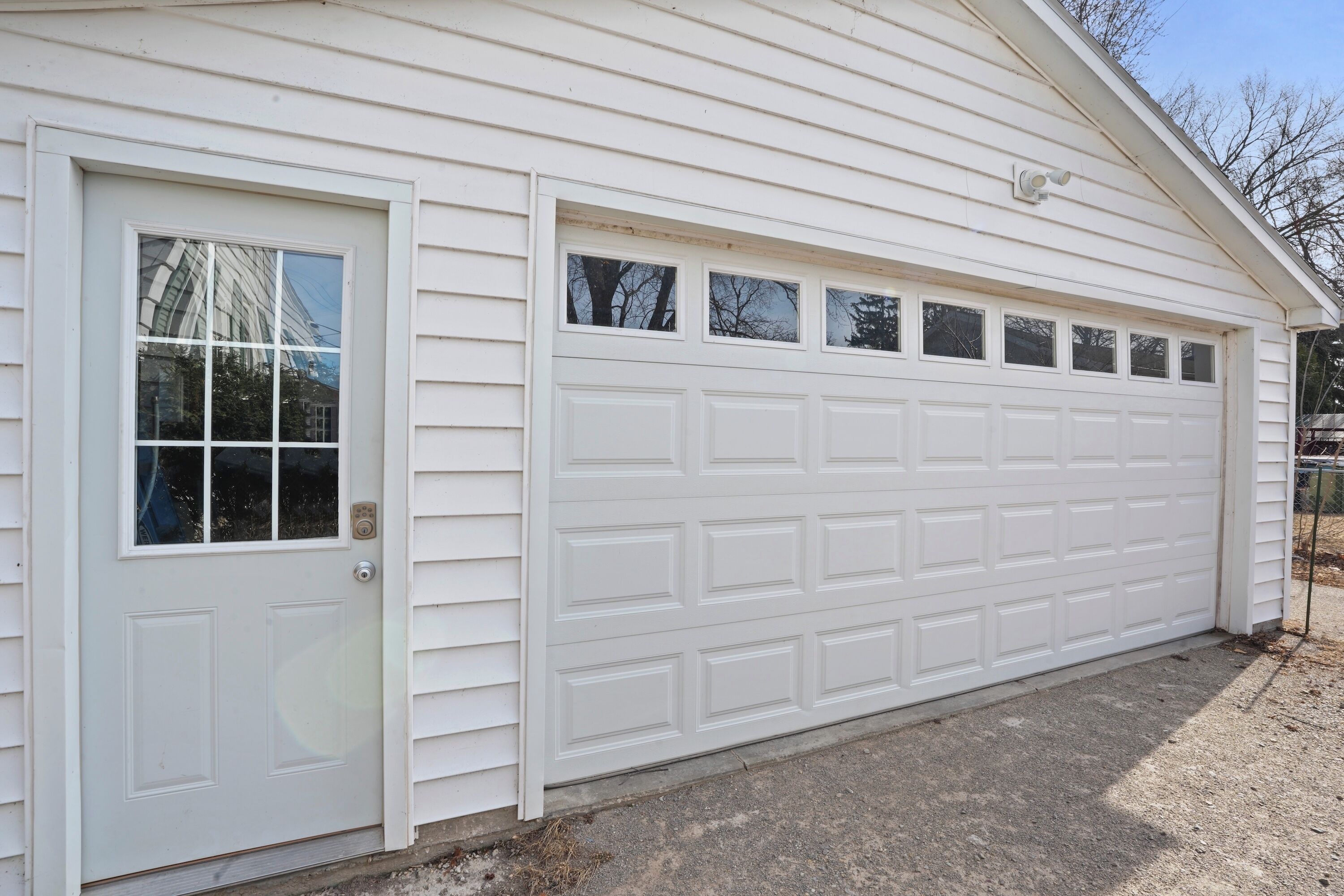 Un garage blanc avec une seule porte et plusieurs fenêtres.
