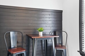 A corner seating area with two metal chairs and a small table, featuring a potted plant on the table.
