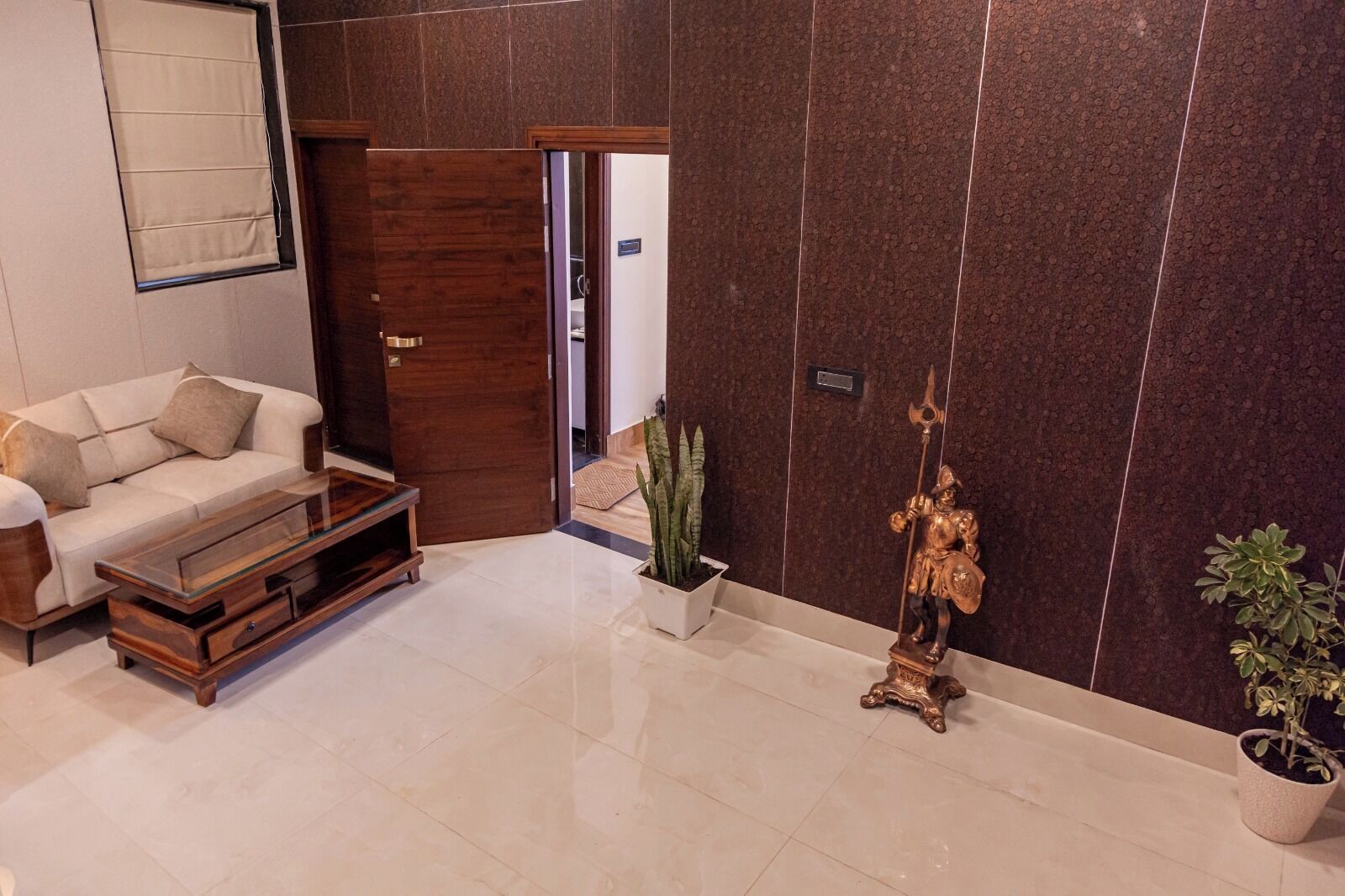 A modern living room with a sofa, coffee table, and decorative items including a statue and plants.