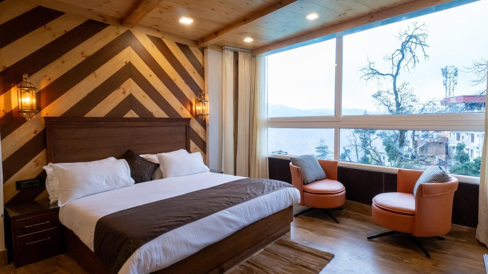 Un dormitorio con una cama grande, dos sillas, techo de madera y una ventana con vistas.