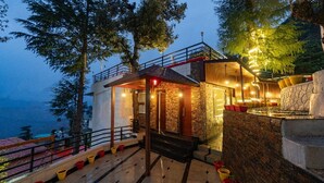 Un edificio moderno con facciata in pietra, un patio in legno e una scalinata che conduce all'ingresso.