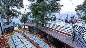 Una terrazza sul tetto con piante in vaso, posti a sedere all'aperto e vista sulle montagne.