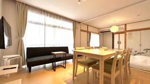 A modern hotel room with a dining area, sofa, and a bed. - FuranoBnB (Furano)