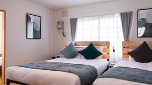 A modern hotel room with two beds, a large window with curtains, and artwork on the walls. - FuranoBnB (Furano)