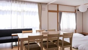 A hotel room with a dining table, four chairs, a sofa, and a bed. - FuranoBnB (Furano)