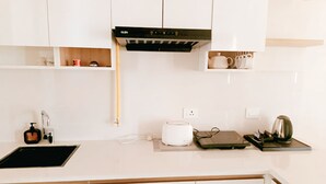 A modern kitchen with white cabinets, a black range hood, a sink, a toaster, and a kettle.