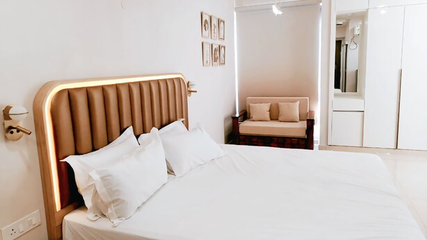A modern bedroom with a large bed, a bedside table, a nightstand, a sofa, and a wardrobe.