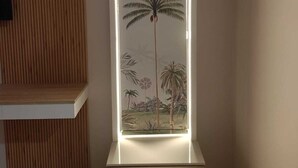 A vertical display with a tropical scene, including palm trees and a bird, illuminated by internal lighting.