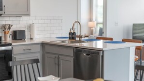 Eine moderne Küche mit eingebautem Geschirrspüler, einer Spüle und einem Essbereich mit Tisch und Stühlen.