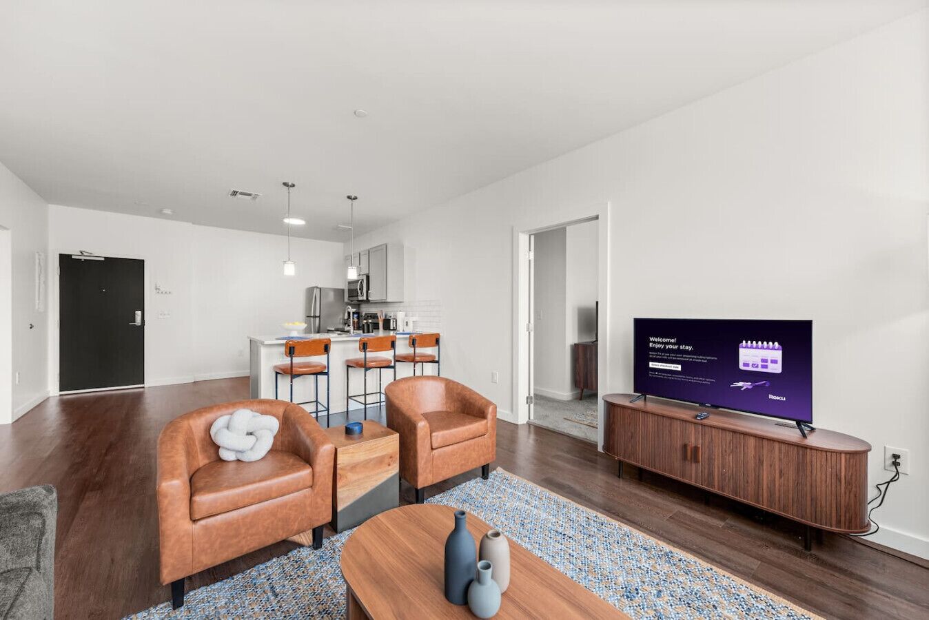 Uma sala de estar moderna com sofás de couro, uma mesa de centro e uma TV de tela plana.