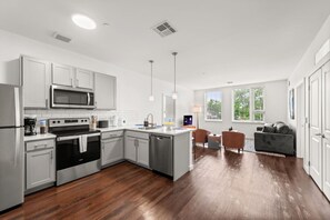 A modern kitchen with stainless steel appliances, a central island, and a dining area with a sofa and chairs.