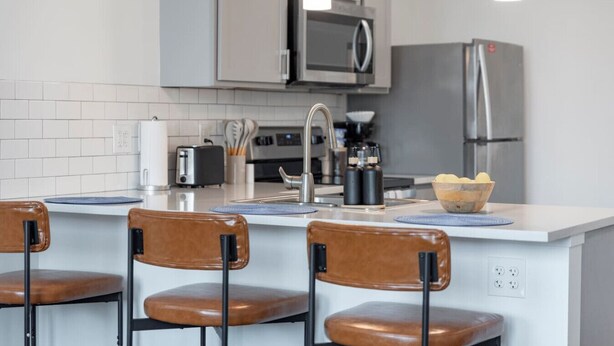 Una cucina moderna con isola centrale, elettrodomestici in acciaio inossidabile e sgabelli da bar.