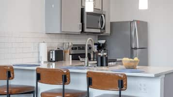 Een moderne keuken met een centraal eiland, roestvrijstalen apparatuur en barkrukken.