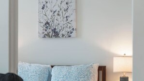Una camera da letto con un letto, un comodino, una lampada e un'opera d'arte appesa al muro.