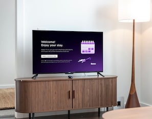 Televisio, joka on sijoitettu puiseen kaappiin, ja jossa on käytössä Roku-käyttöliittymä.