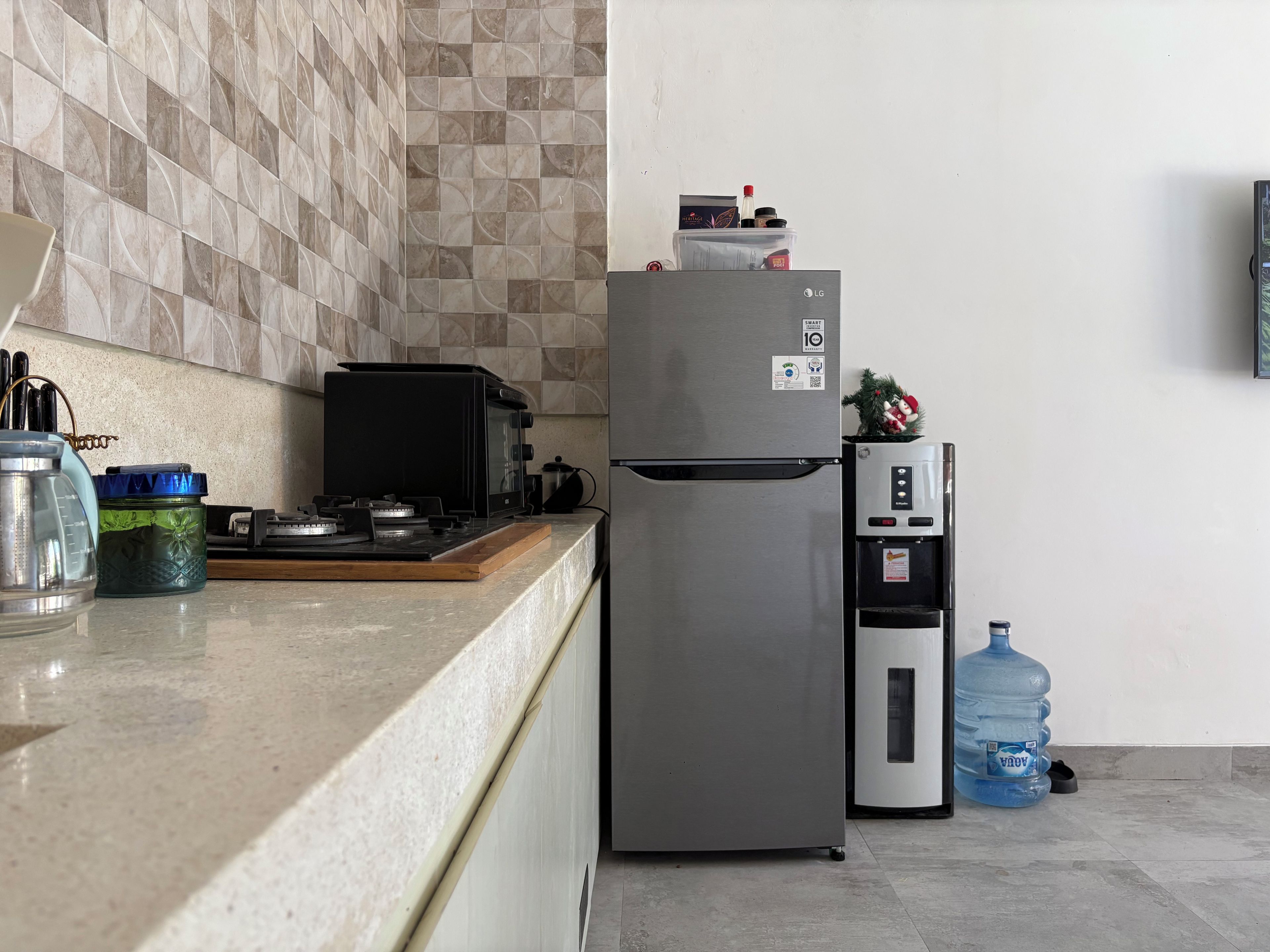 Una cuina amb un frigorífic d'acer inoxidable, una cuina de gas i un dispensador d'aigua.