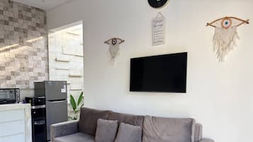 Un espace de vie moderne avec un canapé gris, un téléviseur à écran plat et des éléments décoratifs muraux.