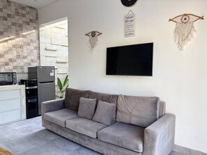 Un espacio de estar moderno con un sofá gris, un televisor de pantalla plana y adornos de pared decorativos.