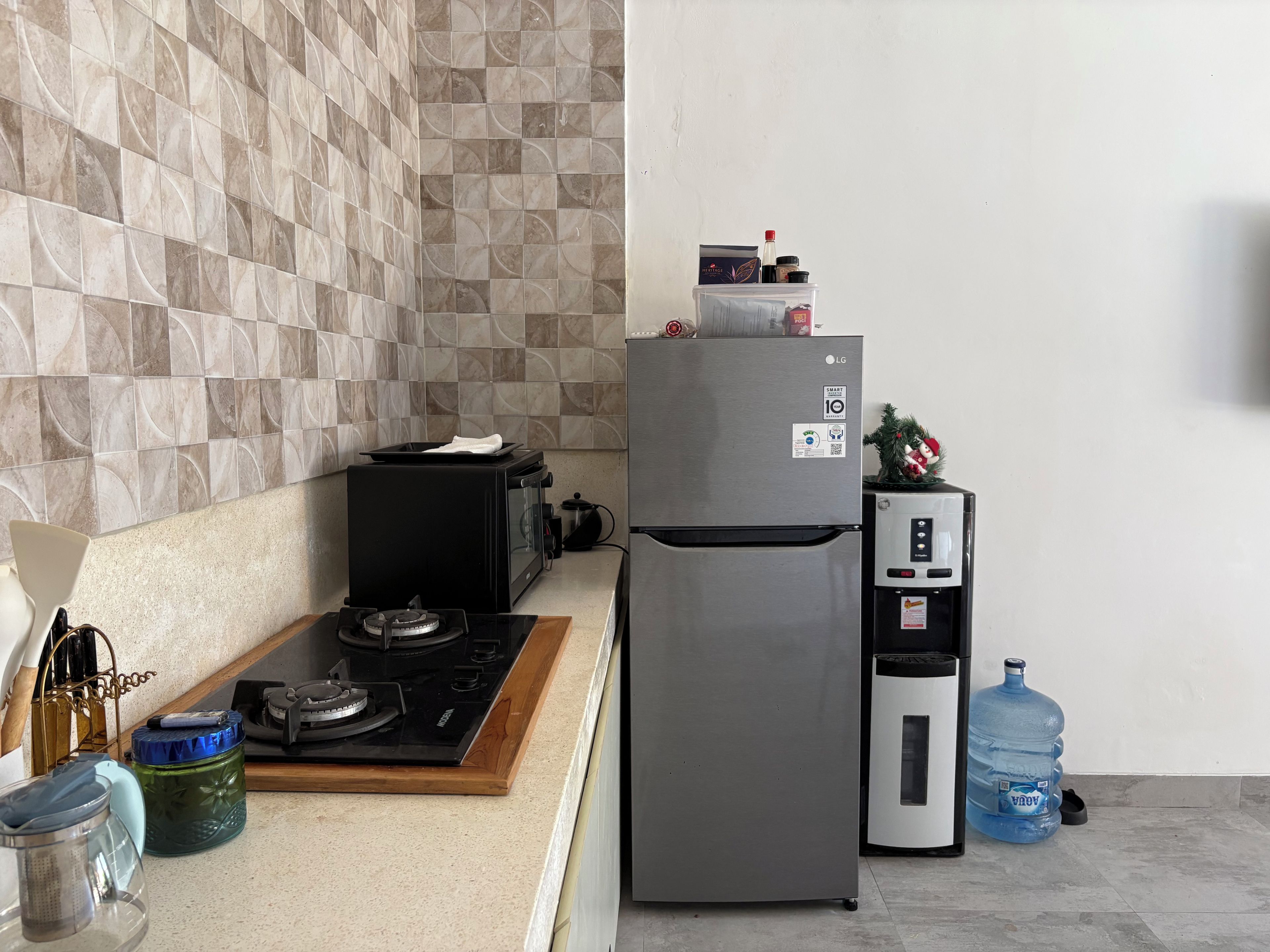 A kitchen with a gas stove, microwave, refrigerator, and water dispenser.
