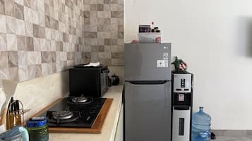 A kitchen with a gas stove, microwave, refrigerator, and water dispenser.