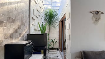 A narrow hallway with a tiled wall, a microwave, a plant, and a couch.