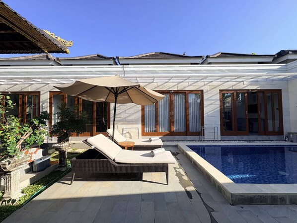 A poolside area with lounge chairs, a pergola, and a swimming pool. - Amy Guesthouse Nusa Dua (Nusa Dua)