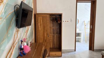 A room with a wooden TV stand, a wooden wardrobe, a remote control, and a small figurine on the wall.