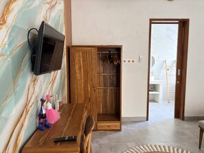A room with a wooden TV stand, a wooden wardrobe, a remote control, and a small figurine on the wall. - Amy Guesthouse Nusa Dua (Nusa Dua)