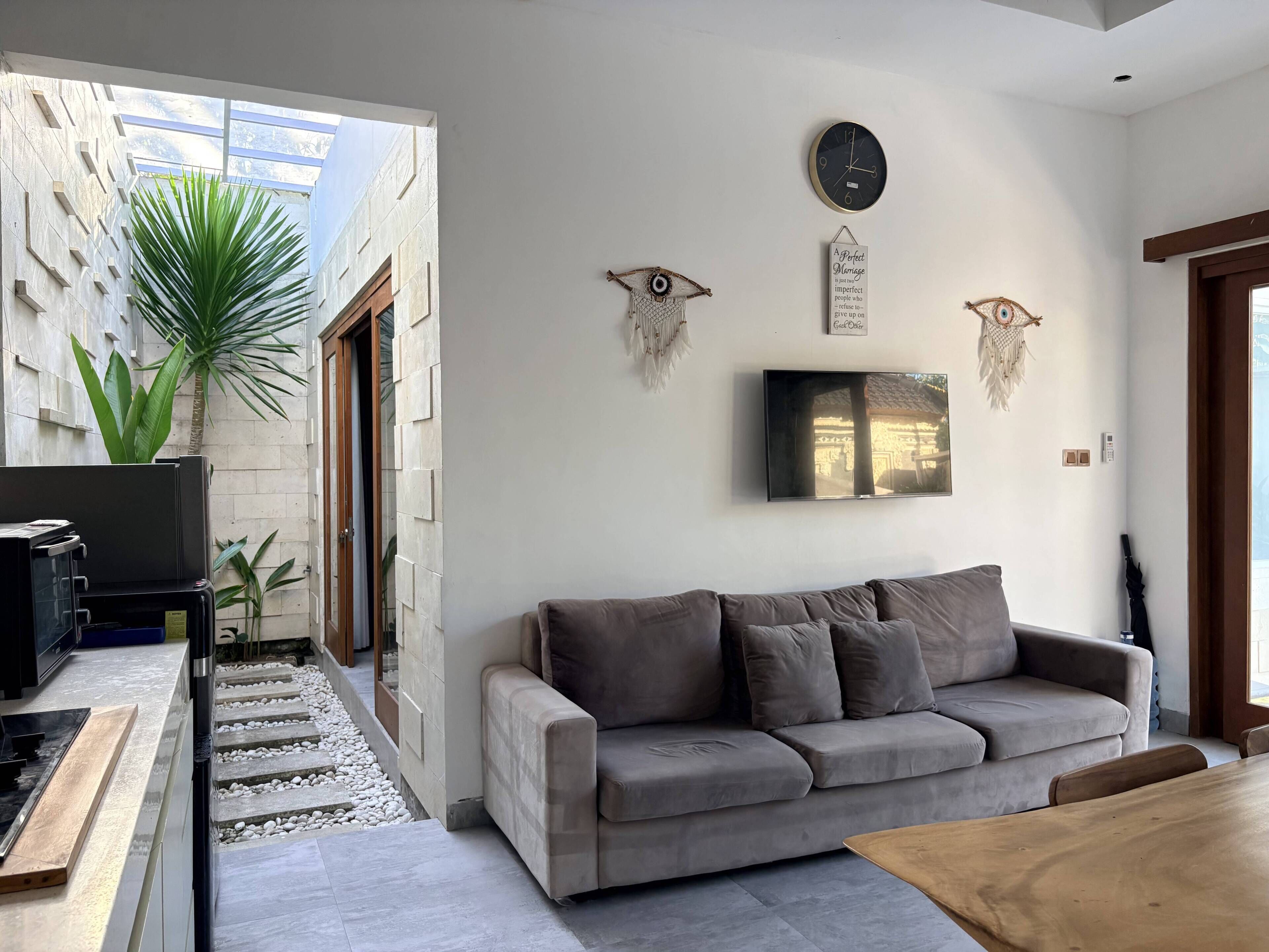 A modern living room with a grey sofa, a flat-screen TV, and decorative wall art.