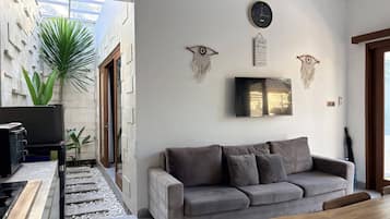 A modern living room with a grey sofa, a flat-screen TV, and decorative wall art.