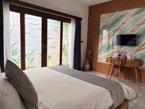 Habitación de hotel con cama, escritorio, televisor y vistas al exterior.