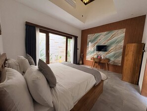 Un dormitorio moderno con una cama grande, un escritorio y un televisor instalado en una pared con diseño de mármol.