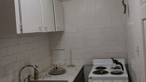 A compact kitchen with white cabinets, a stainless steel sink, a gas stove, and a ceiling light fixture.