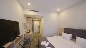Ein Hotelzimmer mit Bett, Fernseher, Schreibtisch und Bad.
