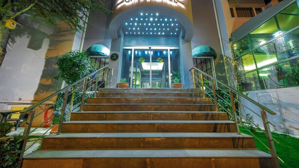 Ein Hotel Eingang mit einem Schild mit der Aufschrift "LETTO CITY HOTEL", einer Treppe, die zum Eingang führt, und Blumentöpfen auf beiden Seiten.